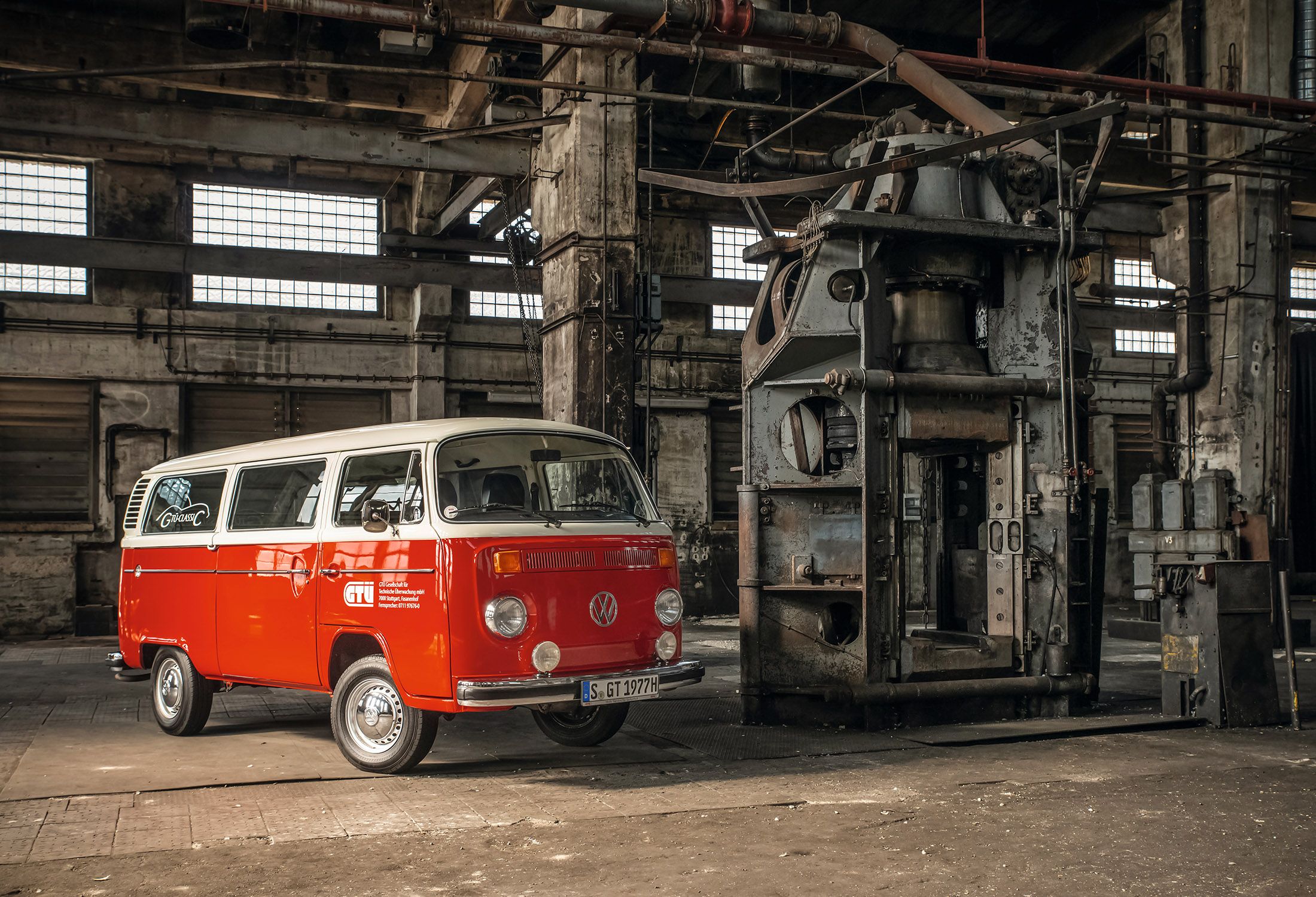 Ein roter Oldtimer VW-Bus steht in einer Werkstatt.