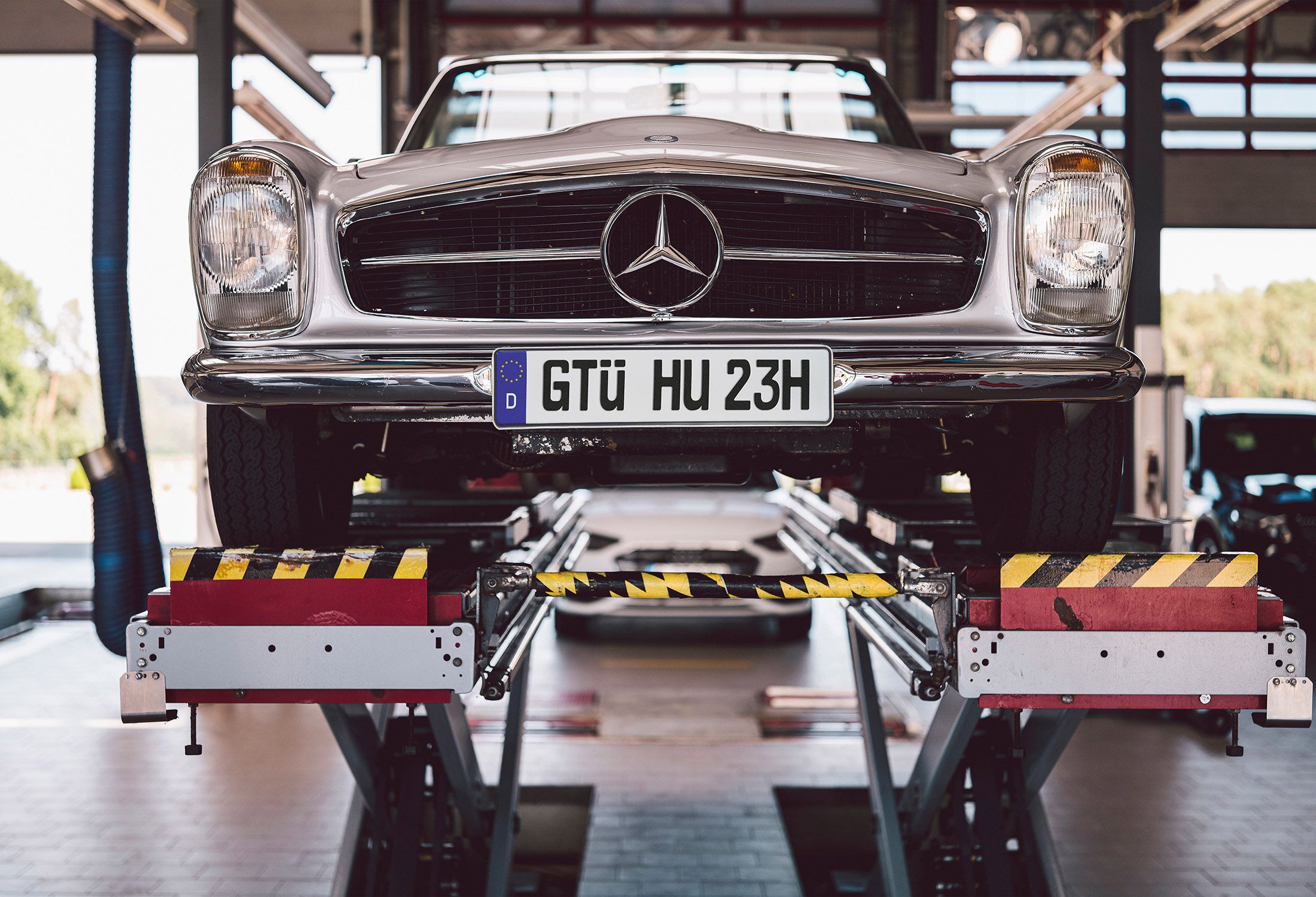 Mercedes Oldtimer steht auf einer Hebebühne in einer Werkstatt.